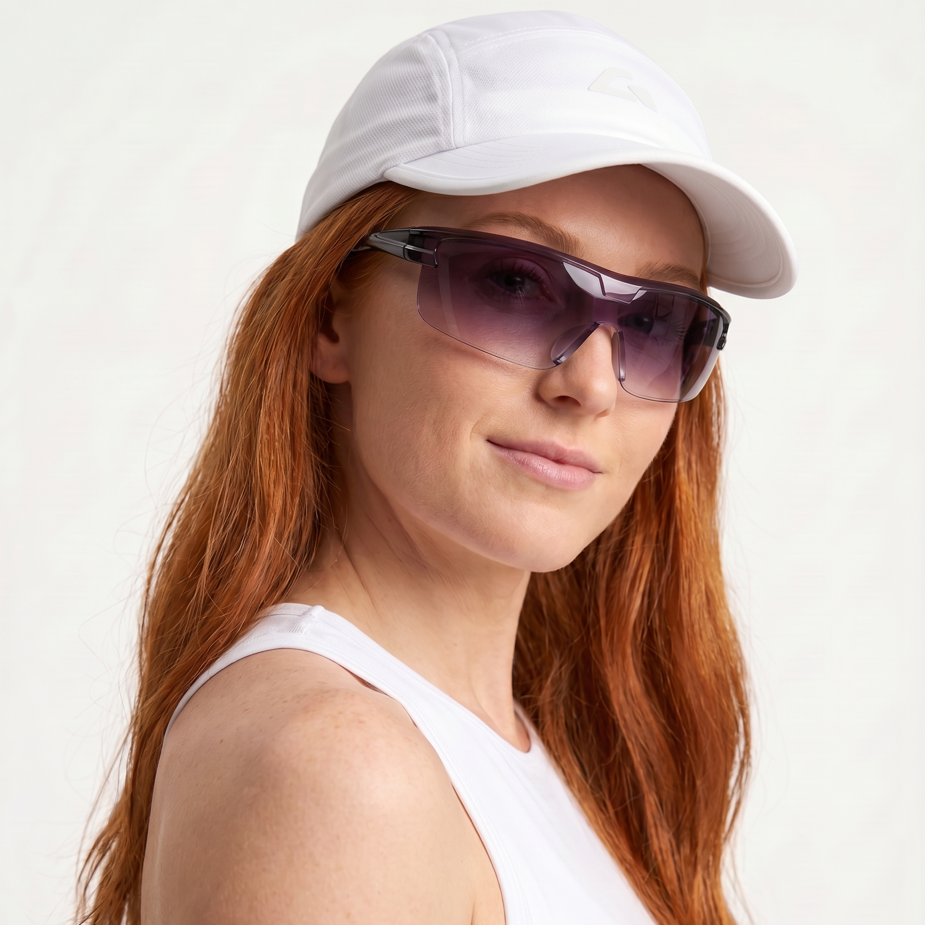 Woman wearing a white cap and sunglasses on a light background