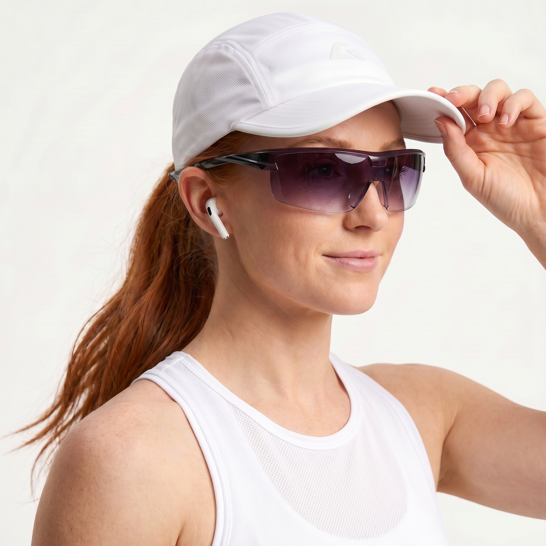 Woman wearing a white cap, sunglasses, and a white tank top on a light gray background